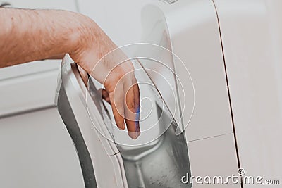 A man in a public place dries his hands in an electric dryer Stock Photo