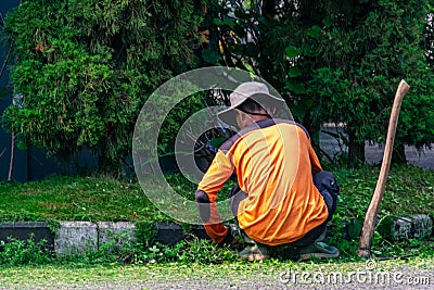 Man public worker tidy up the city street yard with on the street Editorial Stock Photo