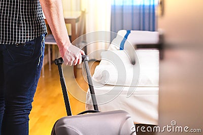 Man pulling suitcase and entering hotel room. Stock Photo