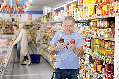 Man purchaser choosing tomato juice in big supermarket Stock Photo