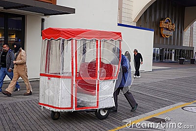 A man pushes a famous rolling chair on the boardwalk in Atlantic City, New Jersey Editorial Stock Photo