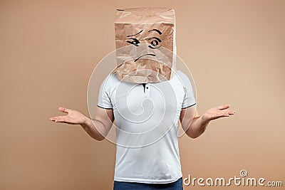 The man put a paper bag on his head, spreads his arms to the sides, despondency, depression. Isolate on yellow background, images Stock Photo