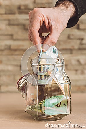 A man puts Euro banknotes in a glass jar - replenishment of family budget Stock Photo