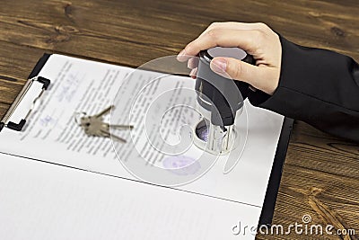 A man puts a seal on documents when buying an apartment, the keys to the apartment contract Stock Photo