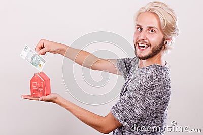 Man putting money into house piggybank Stock Photo