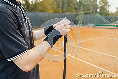Man putting new grip tape on tennis racket. Wrapping finishing tape on racquet. Stock Photo
