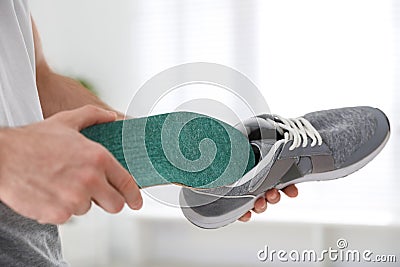 Man putting orthopedic insole into shoe at home Stock Photo