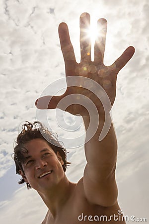 Man Reaching for Sun Flare on Beach Stock Photo