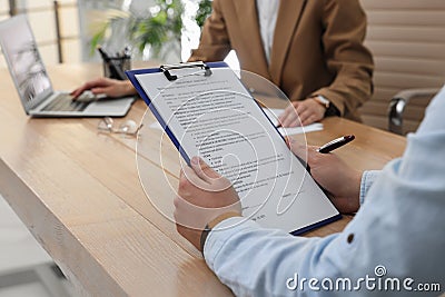 Man reading employment agreement at table in office, closeup. Signing contract Stock Photo