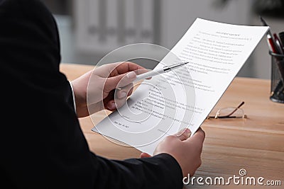 Man reading employment agreement at table in office, closeup. Signing contract Stock Photo