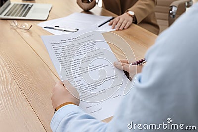 Man reading employment agreement at table in office, closeup. Signing contract Stock Photo