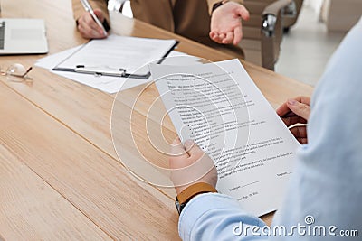 Man reading employment agreement at table in office, closeup. Signing contract Stock Photo