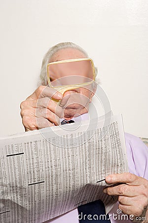 Man reading newspaper with magnifying glass Editorial Stock Photo