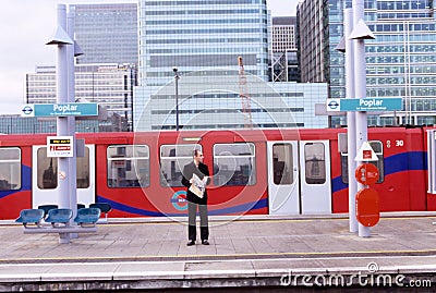 Man reading newspaper, Poplar station, London Editorial Stock Photo