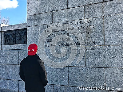 Man reading Nimitz quote on WWII Memorial wall, while wearing a `Make America Great Again` hat. Editorial Stock Photo