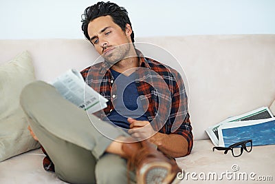Man, reading and relax with newspaper on couch in home, living room and learning about event from media. Calm, weekend Stock Photo