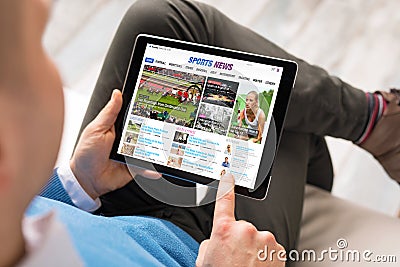 Man reading sports news on tablet. All contents are made up. Stock Photo