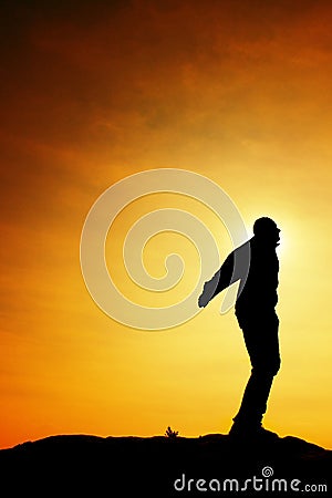 Man ready to jump. Adult crazy man is jumping on colorful sky background.Silhouette of man and beautiful sunset sky. Stock Photo