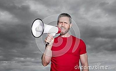 man in red shirt proclaim in loudspeaker on sky background Stock Photo