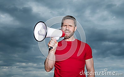 man in red shirt proclaim in loudspeaker on sky background Stock Photo