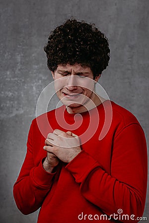 The man in the red sweater is very unhappy, conveys the emotion of grief and despair Stock Photo