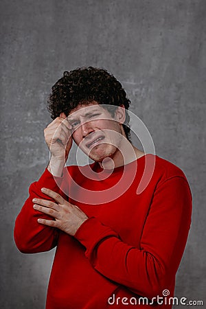 The man in the red sweater is very unhappy, conveys the emotion of grief and despair Stock Photo