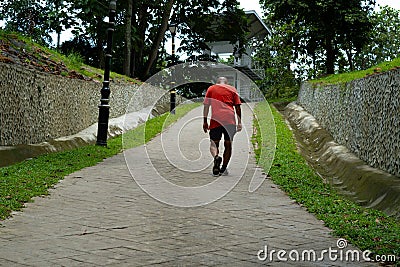 Man in a red t-shirt walking in a green public park in Kepong, Kuala Lumpur, Malaysia. Editorial Stock Photo