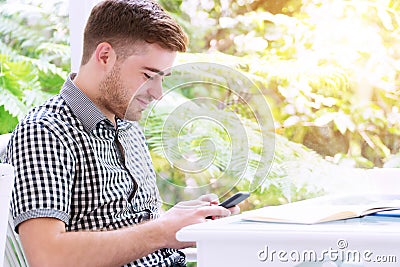 Man relaxed using smartphone with cup coffee working at home. Business young man browsing on smart phone in living Stock Photo