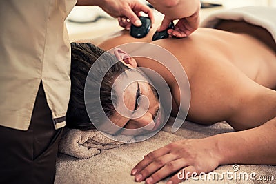 Man relaxing under the stimulating effects of a traditional hot stone massage Stock Photo