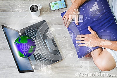 Man relaxing using internet via laptop computer with globe, networks, mobile phone with gps and hot coffee cup on wooden floor Stock Photo