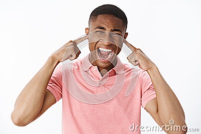 Man releasing stress cannot handle town noise. Displeased and fed up intense african american guy closing ears and Stock Photo