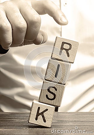 Man removes blocks with the word Risk. The concept of reducing possible risks. Insurance, stability support. Legal protection of Stock Photo