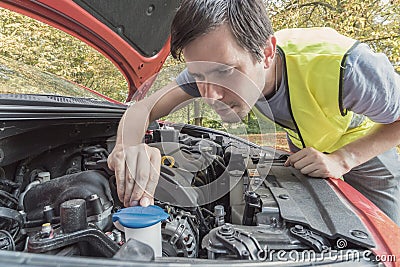 Man is repairing car and checking engine coolant Stock Photo