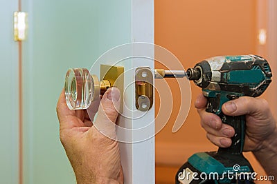 Man repairing the doorknob closeup of worker hands installing new door locker Stock Photo
