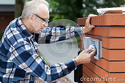 Man repairing intercom at the gate Stock Photo