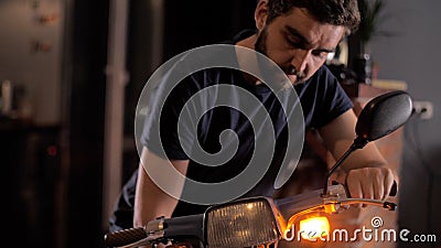 Man repairs a blue scooter or motorcycle in home brick garage. Stock Photo