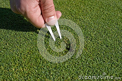 Man Repairs Divot on Golf Green - Horizontal Stock Photo