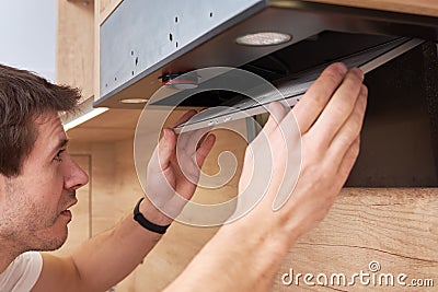 Man repairs hood in kitchen. Replacement filter in cooker hood Editorial Stock Photo