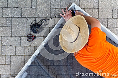 Man replacing damaged wire mesh on a screen door Stock Photo