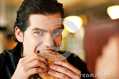 Man in restaurant eating hamburger Stock Photo