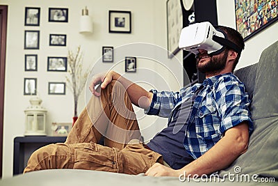 Man resting on comfortable sofa wearing VR headset glasses Stock Photo