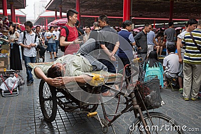 Man resting on a rickshaw of the Panjiayuan Antique Market, Beijing Editorial Stock Photo