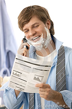 Man reviewing document while shaving Stock Photo