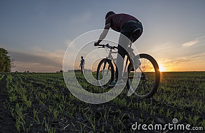 Man ride a bicycle in sunset and man standing and watching. Riding a Bicycle at Sunset. Healthy Lifestyle Concept. Male Editorial Stock Photo