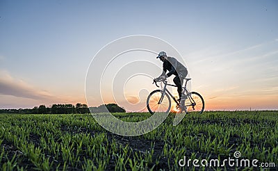 Man ride a bicycle in sunset. Riding a Bicycle at Sunset. Healthy Lifestyle Concept. Male ride bicycle in sun set. Biker Editorial Stock Photo