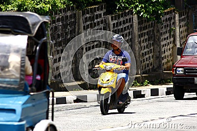 A man rides his scooter on an uphill road in Antipolo City. Editorial Stock Photo