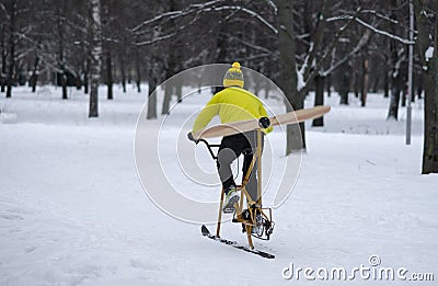A man rides a homemade bicycle with a propeller in the snow.Snowbike in the park. Bike with skis. Stock Photo