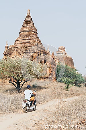 Man riding electric scooter towards temples and pagodas of ancient Bagan in Myanmar Editorial Stock Photo