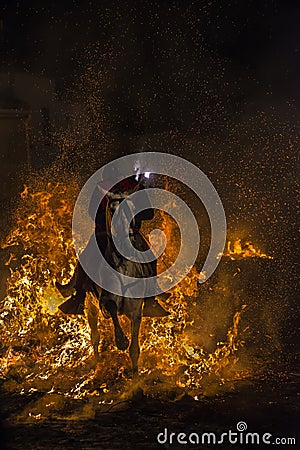 A man riding his horse jumping throug the fire Editorial Stock Photo