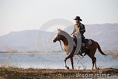 Cowboy on his horse walking through dust in the lake Stock Photo